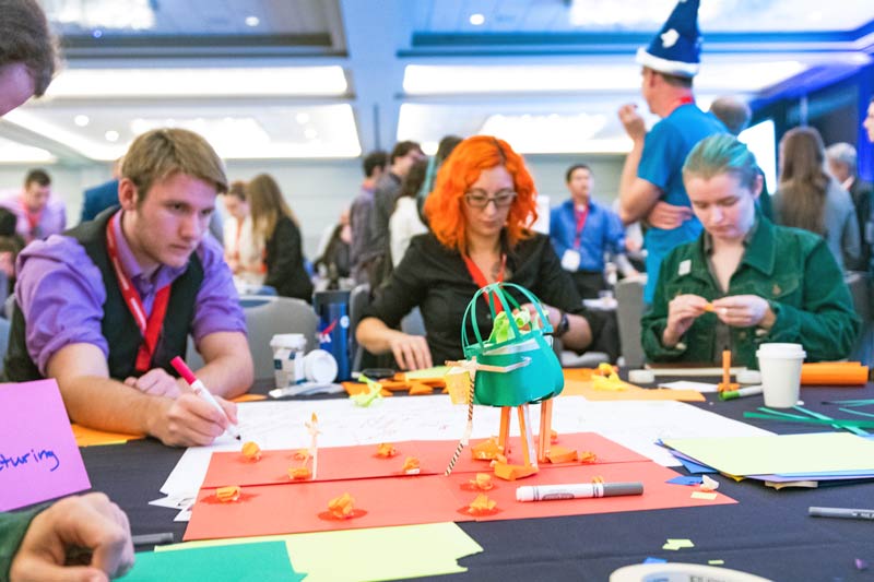 Attendees develop models of innovative solutions using construction paper and tape.