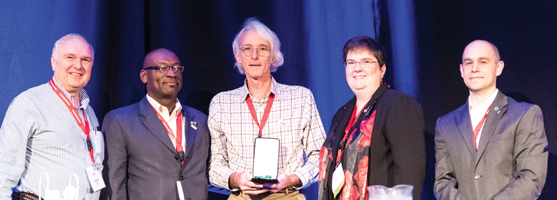 Neuenschwander (Center) with (L to R) AIP CEO Robert G.W. Brown, Sigma Pi Sigma President Willie S. Rockward, Society of Physics Students President DJ Wagner, and SPS &amp; Sigma Pi Sigma Director Brad R. Conrad.