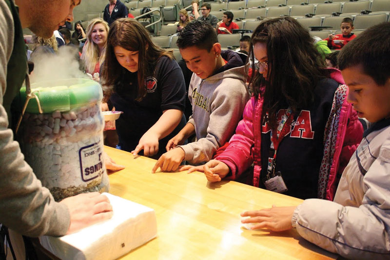 Students from the Cesar Chavez Academy wait patiently as liquid nitrogen is used as a cooling agent in the production of the ice cream they are about to eat.