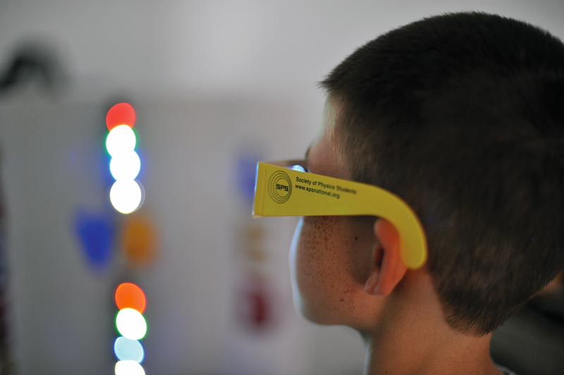 A young scientist looking at the world through “rainbow” diffraction glasses.  Photo by Alec Lindman.