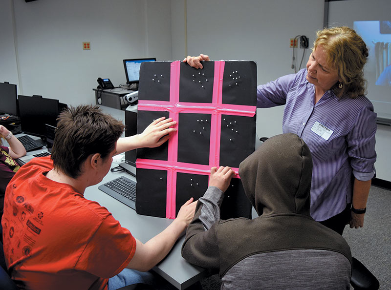 Kathy Gustavson, a retired physics teacher and IDATA curriculum developer, uses a tactile model developed by the IDATA team to teach participants from the Wisconsin School for the Blind how a charge-coupled device camera works, enabling them to help with software design. Photo courtesy of Kate Meredith, GLAS Education.