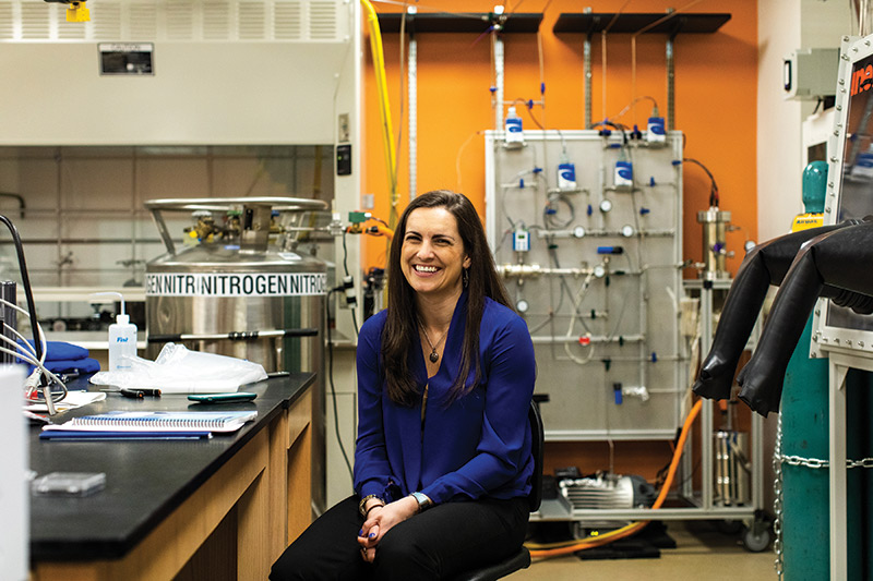 Sarah M. Hörst sits in front of the planetary atmospheric simulation chamber in her lab. Photo by Justin Tsucalas, Plaid Photo.