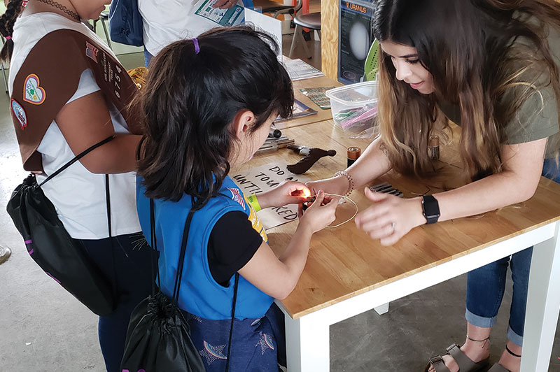 An SPS member at Texas A&amp;M University–Commerce (right) helps Girl Scouts light up a miniature light bulb during an event with the Girl Scouts of Northeast Texas. 