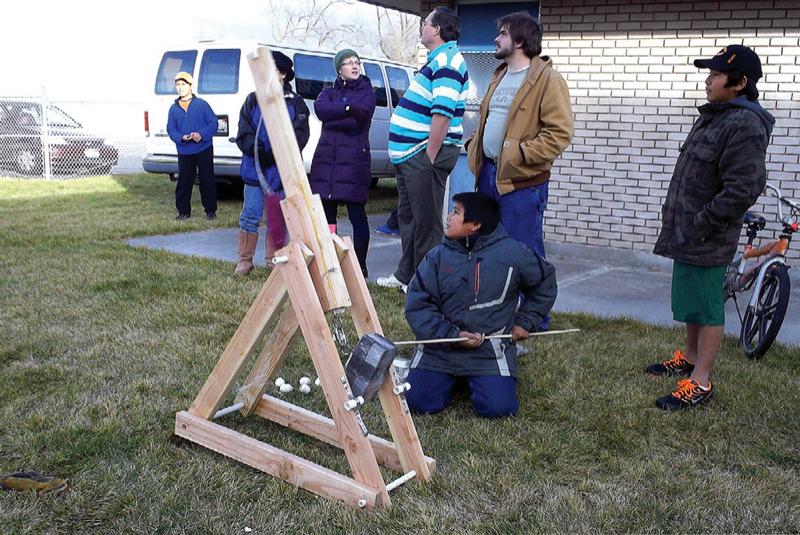 An elementary school student triggers his homemade trebuchet. Photo by Jason Stock.