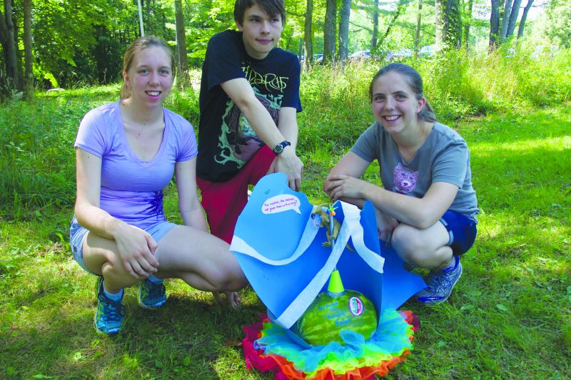 Students Emily Stump, Ian Shen, and Iona Binnie pose with “Melanie the Melodic Melon.” The cheer reads, “The melons, the melons, we greet them with a song!” and is a parody of Williams’ alma mater song. Photo by Ellery Galvin.